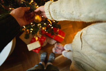 Couple holds in hands xmas toy golden ball to decorate xmas tree. Winter holiday, preparing to celebrate Christmas and New Year at home
