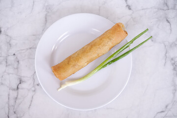 Spring roll closeup of Chinese style with leek on a white plate