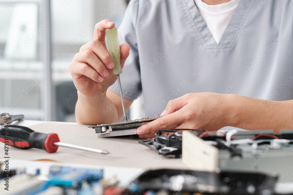 Poster Hands of female troubleshooting technician fixing tiny details of computer hardware while sitting by workplace