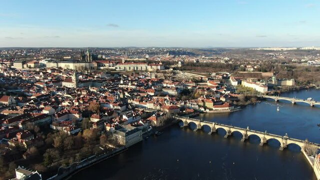 4k cinematic aerial video of the Prague castle, moldau river and charles bridge on a sunny winter day with blue sky
