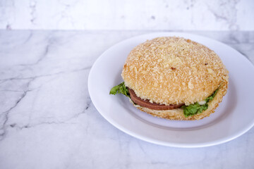 Simple beef burger  with ham and lettuce are served on a white plate. Bakery, Fast food concept. Street food concept.