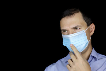 Portrait of pensive man in mask on black background. Life during coronavirus pandemic