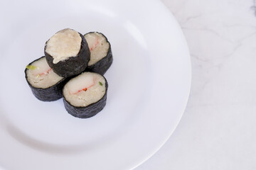 Chicken nori rolls or sushi rolls with shrimp, cheese, caviar, chicken, soy sauce, nori, wasabi on a white plate