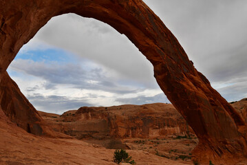 Corona Arch near Moab at sunset after thunderstorm. Typical Utah red rock formations.
