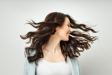 Portrait of a beautiful cheerful brunette with flowing curly hair, smiling, laughing, on a white background.