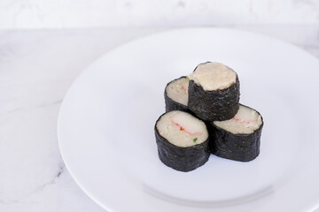 Chicken nori rolls or sushi rolls with shrimp, cheese, caviar, chicken, soy sauce, nori, wasabi on a white plate