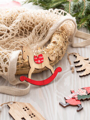 Christmas diy straw wreath in string bag, handmade wooden toys on white rustic table. Selective focus. Festive sustainable eco preparation.