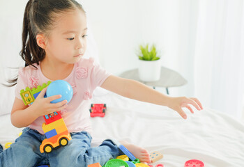 Little cute asia girl playing plastic colorful toys