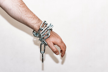 Hand with chain,the chain hanging from the bottom,gray background.Copy space,selective focus.