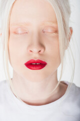 Portrait of young albino woman with red lips closing eyes isolated on white.