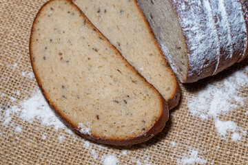 a loaf cut of wheat bread and two slices cut on a linen beige canvas.Close up.Top view.