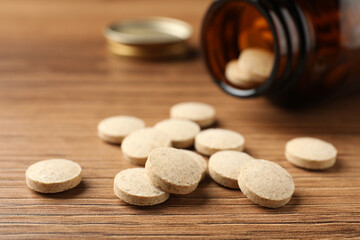 Fototapeta na wymiar Dietary supplement pills on wooden table, closeup