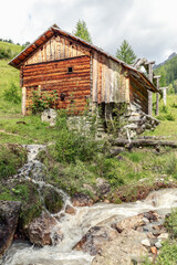 Ancient water mill on the banks of a mountain stream in a park Mill Valley (Val di Morins). Longiaru, Italy (Vertical photo)