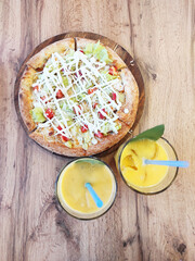 Vegetarian pizza with two cocktails on a wooden table