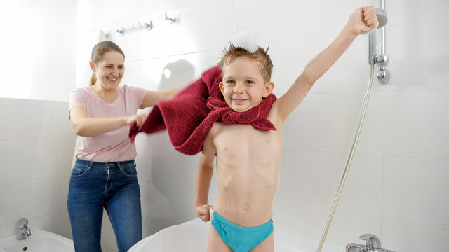 Funny little boy pretending to be superhero with mother in bathroom. Concept of family time, children development and fun at home