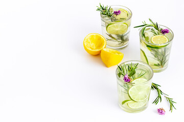 A lot of glasses of lemonade with summer herbs and lemon slices