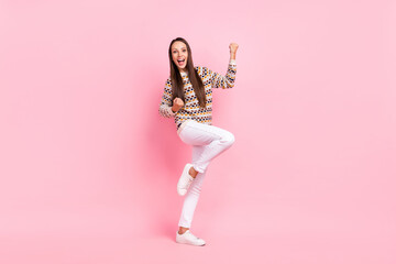 Photo of lucky pretty young woman wear dotted sweater smiling walking rising fists isolated pink color background