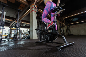 Fototapeta na wymiar Intensive workout fit woman with air bike in gym