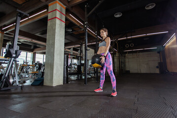 Obraz na płótnie Canvas Fit woman is exercising with medicine ball in modern gym. Strong body