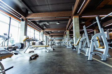Modern gym interior with fitness equipment and exercise machines. Sports hall with large windows