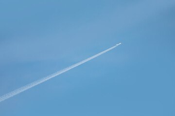 Trail of white smoke from the airplane in the blue sky
