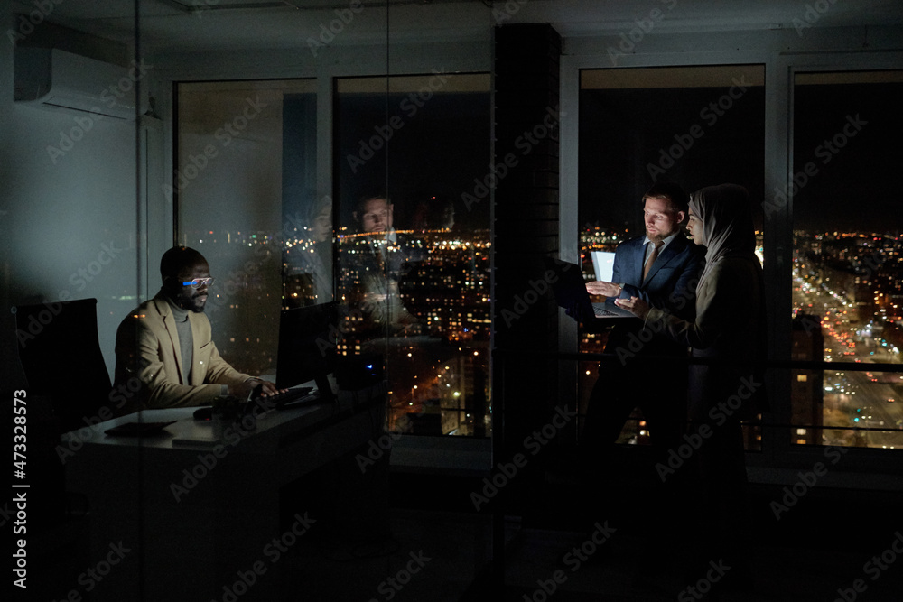 Aufkleber group of young intercultural co-workers computing in large openspace office at night