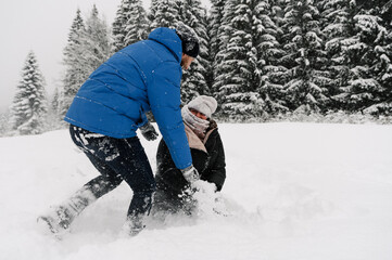 Walk in winter. Embracing couple enjoying snowfall. Man and woman playing with snow in the frosty forest. Romantic date in winter time.Christmas mood of a young family.  Love and leisure concept
