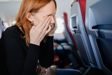 a sleepy woman rubs eyes with hands in an airplane seat. long flights.