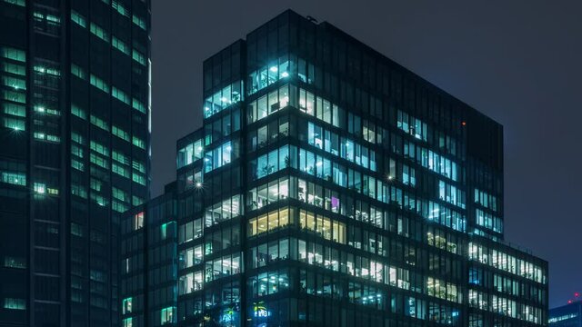 Time lapse day to night transition blinking office windows lights in business center building downtown. Corporate business, high skyscraper glass surface. Light in building windows turn on and off