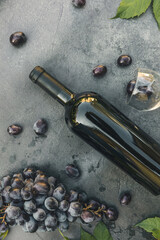 Bottle of red wine, green vine, wineglass and ripe grape on vintage dark stone table background. Top view copy space for text. Wine shop wine bar winery or wine tasting concept