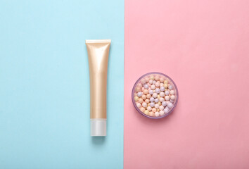 Tube of foundation and balls of powder on pink blue pastel background. Cosmetics. Top view