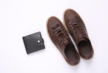 Mens brown leather sneakers and black purse on gray background