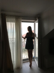 A silhouette of a girl in the window, thinking, dreaming. looking through.