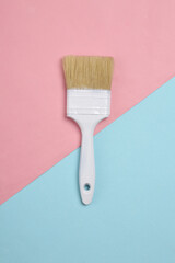 Paint brush on a blue-pink pastel background. Top view