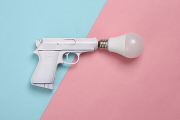 White gun with light bub on blue-pink pastel background. Minimal, creative layout, top view