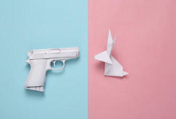 White gun with origami rabbit on blue pink background. Minimal, creative layout, say no war