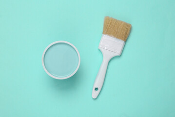 Can of paint with paintbrush on turquoise background