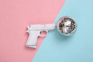 Gun with disco ball on pink blue background. Party concept. Creative minimal layout. Top view