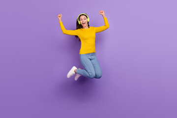Fototapeta na wymiar Full length photo of young girl have fun jump rejoice victory listen radio earphones isolated over purple color background