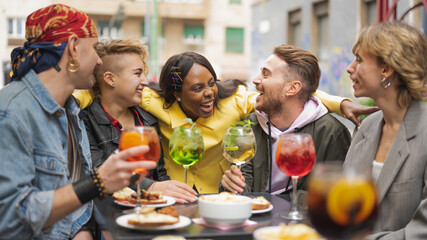 Five young happy people enjoying time together, diverse culture students celebrathing something at pub, drinking cocktail and eating snack, social inclusion, multicultural and gay pride concept - Powered by Adobe