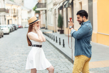 Naklejka premium Hispanic man photographs woman on European street. Tourism, travel concept