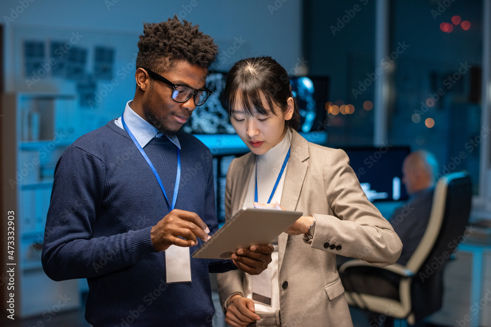 Poster two young interracial colleagues preparing presentation while scrolling through online information i