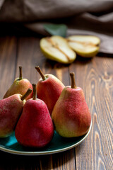 Ripe red pears on a blue plate on a wooden table . Close up.