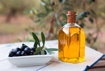 black ripe olives, olive oil in a glass traditional bottle on table in an olive garden