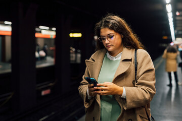 Young female commuter using mobile phone at railroad station platform