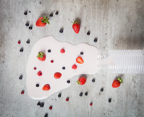 A view from above of berry yogurt spilled on a concrete surface and berries scattered on it.