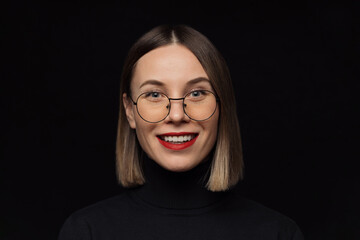 Close up smiling woman portrait wearing glasses with black frames, with red lips on black...