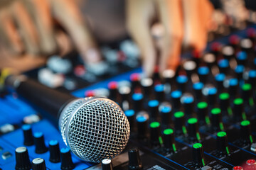Microphone close-up with professional hands are adjusting volume sound of mixer