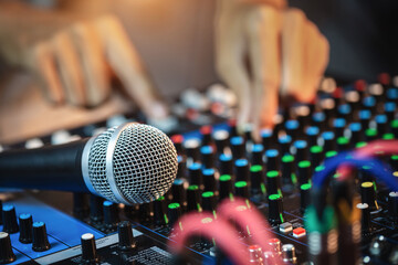 Microphone close-up with professional hands are adjusting volume sound of mixer