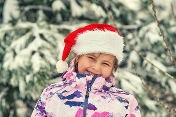 Happy little girl in Santa hat on the street